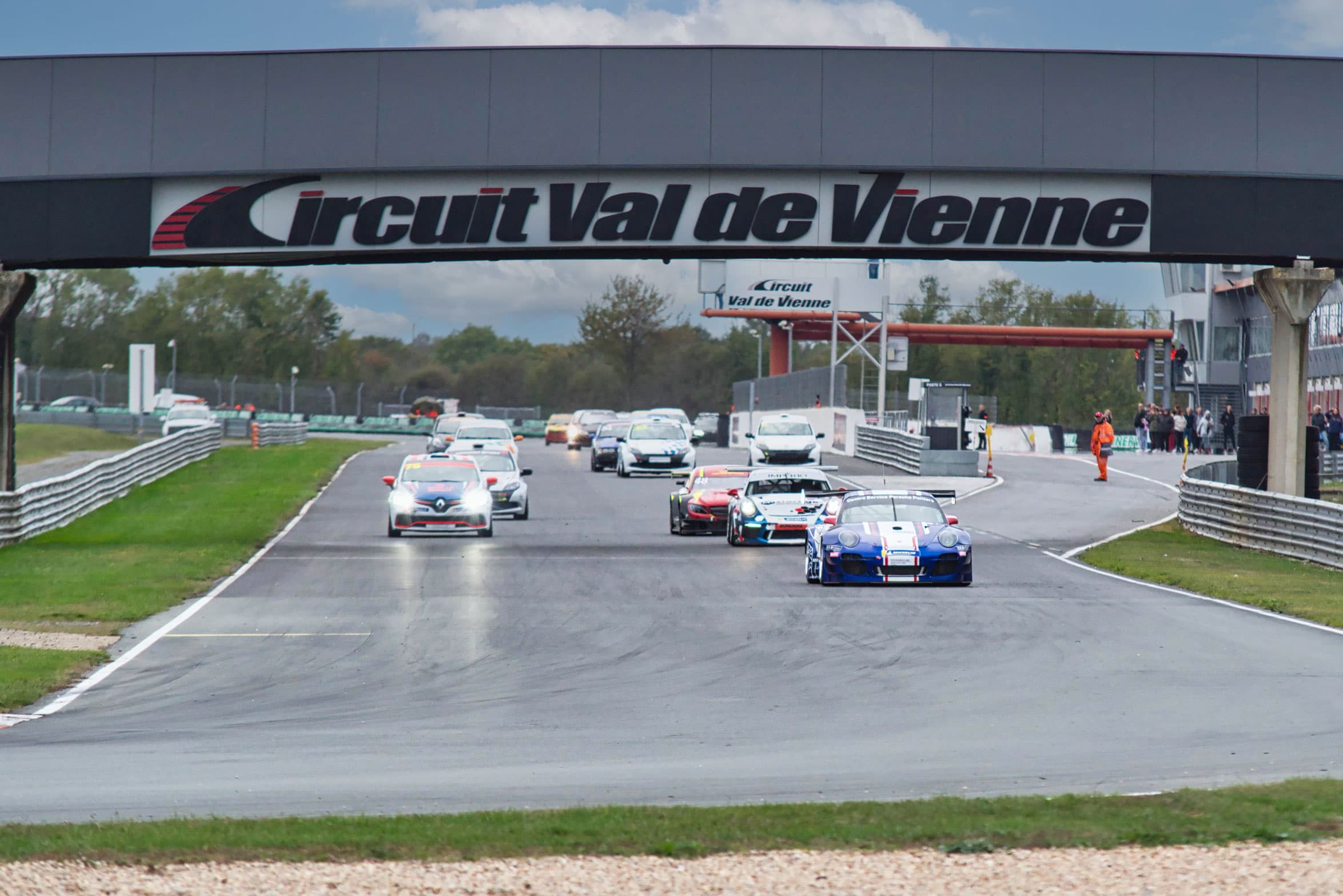 Peloton de voitures de course passant sous la ligne d'arrivée du Circuit du Val de Vienne